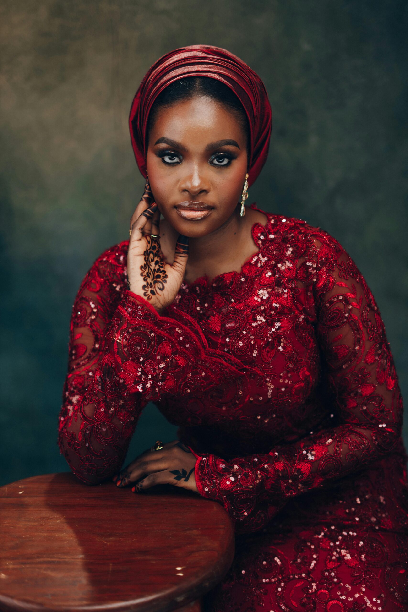 Stunning Nigerian bride in red traditional dress with intricate henna designs.